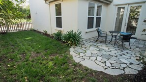 Ein Patio mit Steinboden, einem kleinen Tisch und zwei Stühlen.