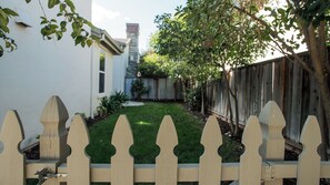 Ein Garten mit Holzzaun, Rasen und einem Haus im Hintergrund.