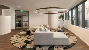 En modern entréhall med en rund sittgrupp, ett stort fönster och en cirkelformad lampa.