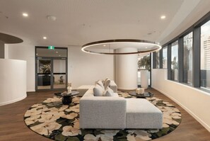 Eine moderne Lobby mit einer runden Sitzecke, einem großen Fenster und einer runden Leuchte.