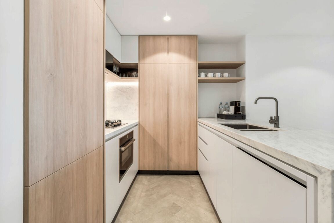 Une cuisine moderne avec des meubles en bois, un plan de travail en marbre et un four encastré.