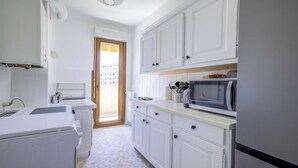 Una cocina con armarios blancos, un microondas y un horno empotrado.