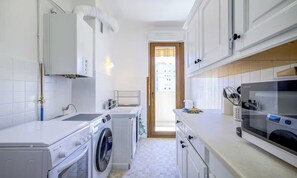 Eine moderne Küche mit Waschmaschine, Mikrowelle und Kaffeemaschine.