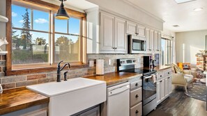 A modern kitchen with a large window, built-in appliances, and a stone backsplash. - Highland Park Panorama by Avantstay Game Room + Panoramic Views Wine Country (Paso Robles)