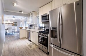 A modern kitchen with stainless steel appliances, wooden cabinets, and a central island. - Sunny Boynton Oasis: Pool, Tiki Hut & Paradise! (Boynton Beach)