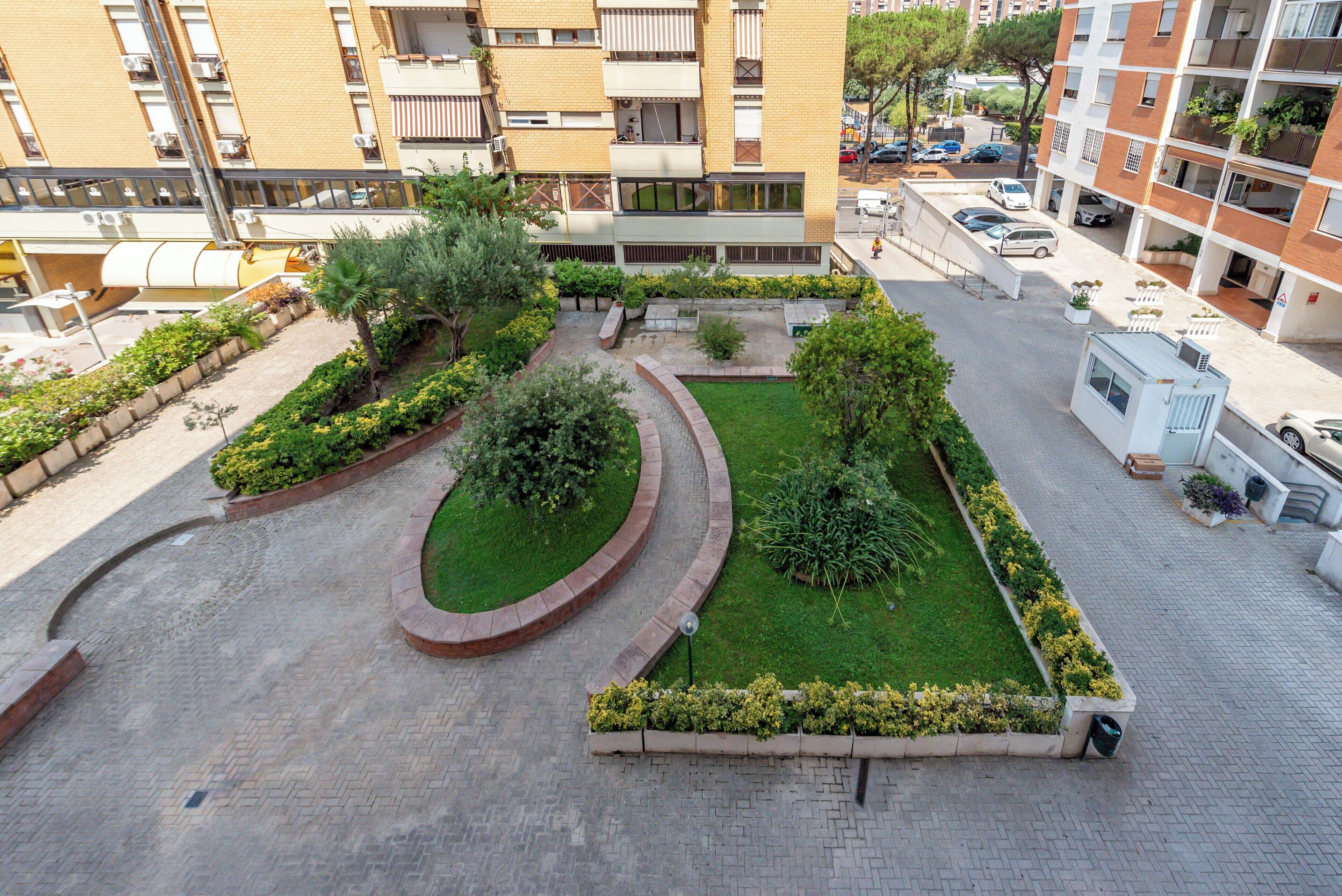 A courtyard with a central lawn, surrounded by brick pathways and bordered by greenery.