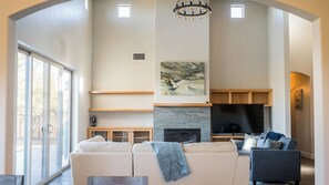 Ein geräumiges Wohnzimmer mit Kamin, großem Flachbildfernseher und einer gemütlichen Sitzecke.