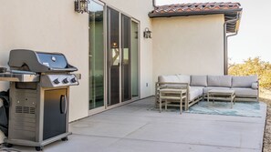 Eine Terrasse im Freien mit Grill, einer Couch und einem Tisch.