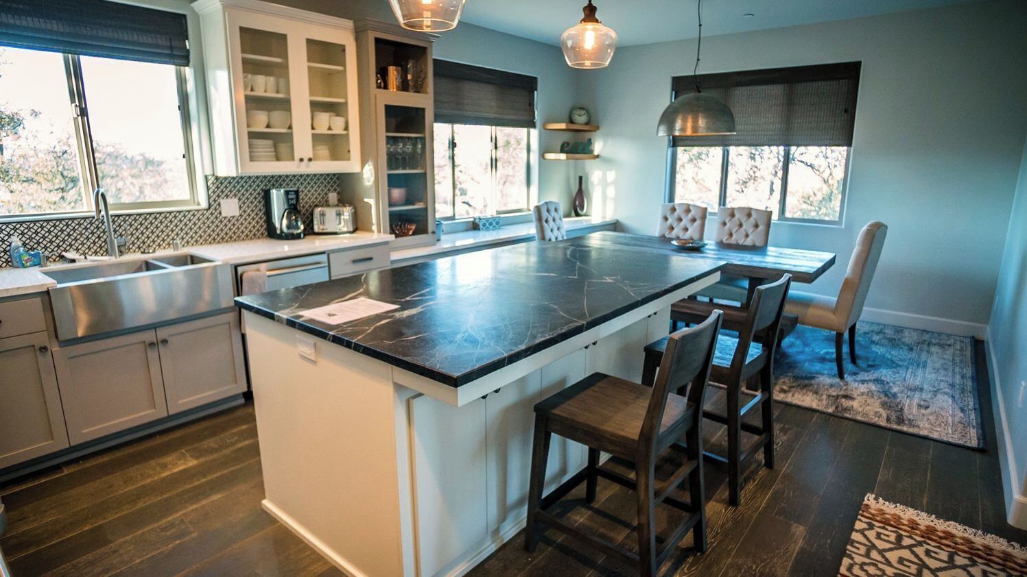 A modern kitchen with a central island, built-in cabinets, and a dining area with chairs.