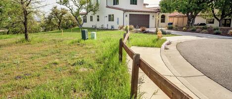 Una casa de dos pisos con garaje, rodeada de césped y una valla de madera.