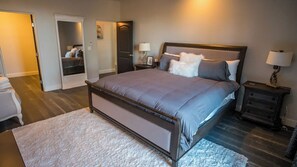 Ein Schlafzimmer mit einem großen Bett, einem Nachttisch, einer Kommode und einem begehbaren Kleiderschrank.