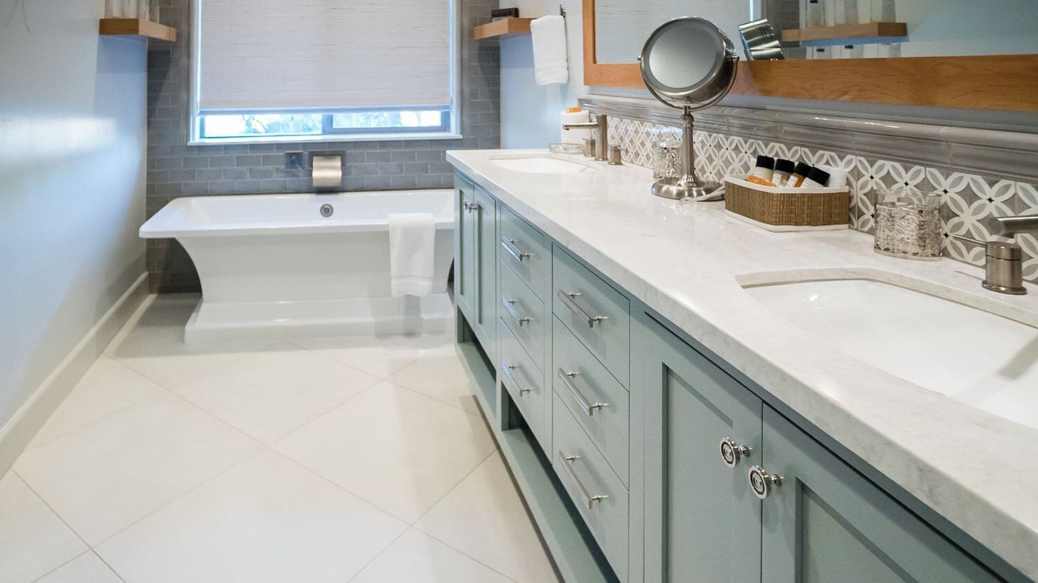 A modern bathroom with a bathtub, vanity with a mirror, and a tiled floor.