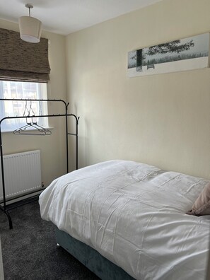 A bedroom with a bed, a radiator, a wall-mounted picture, and a ceiling light fixture. - Stylish 3-Bed Home | Free Parking | Near Etihad Stadium & Co-op Live Arena (Manchester)