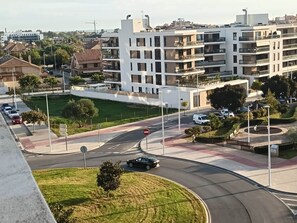 A multi-level residential building with balconies, a roundabout with a no-entry sign, and a parking area with cars. - Encalma vacacional El Ático, terraza,garaje,playa (Port de Sagunt)