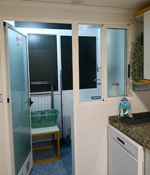 A compact kitchen with a sink, countertop, and a small window. - Encalma vacacional El Ático, terraza,garaje,playa (Port de Sagunt)