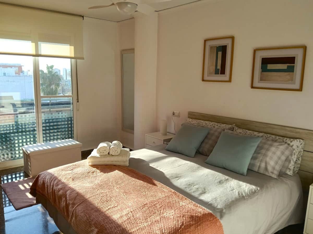 Ein Schlafzimmer mit einem Bett, einem Nachttisch, einem Fenster und einer Tür.
