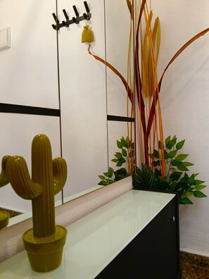 Un intérieur moderne au design minimaliste, agrémenté d’une sculpture de cactus, d’une composition florale et d’un luminaire fixé au mur.