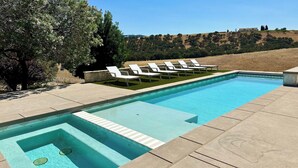 A rectangular swimming pool with a clear blue waterline, surrounded by a stone deck. There are white lounge chairs aligned along the pool's edge. - Tour de Rouge by Avantstay Pool + Spa + Firepit Paso Robles Wine (Paso Robles)
