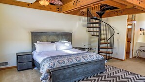 A bedroom with a large bed, a wooden headboard, a built-in nightstand, a black spiral staircase, and a herringbone-patterned rug. - Tour de Rouge by Avantstay Pool + Spa + Firepit Paso Robles Wine (Paso Robles)
