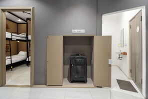 A hotel room with a bunk bed, a suitcase, and a sign indicating a female toilet and shower.