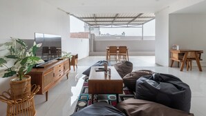A modern living room with a sofa, coffee table, and a television on a wooden cabinet. - New Hostel Braga (Bandung)