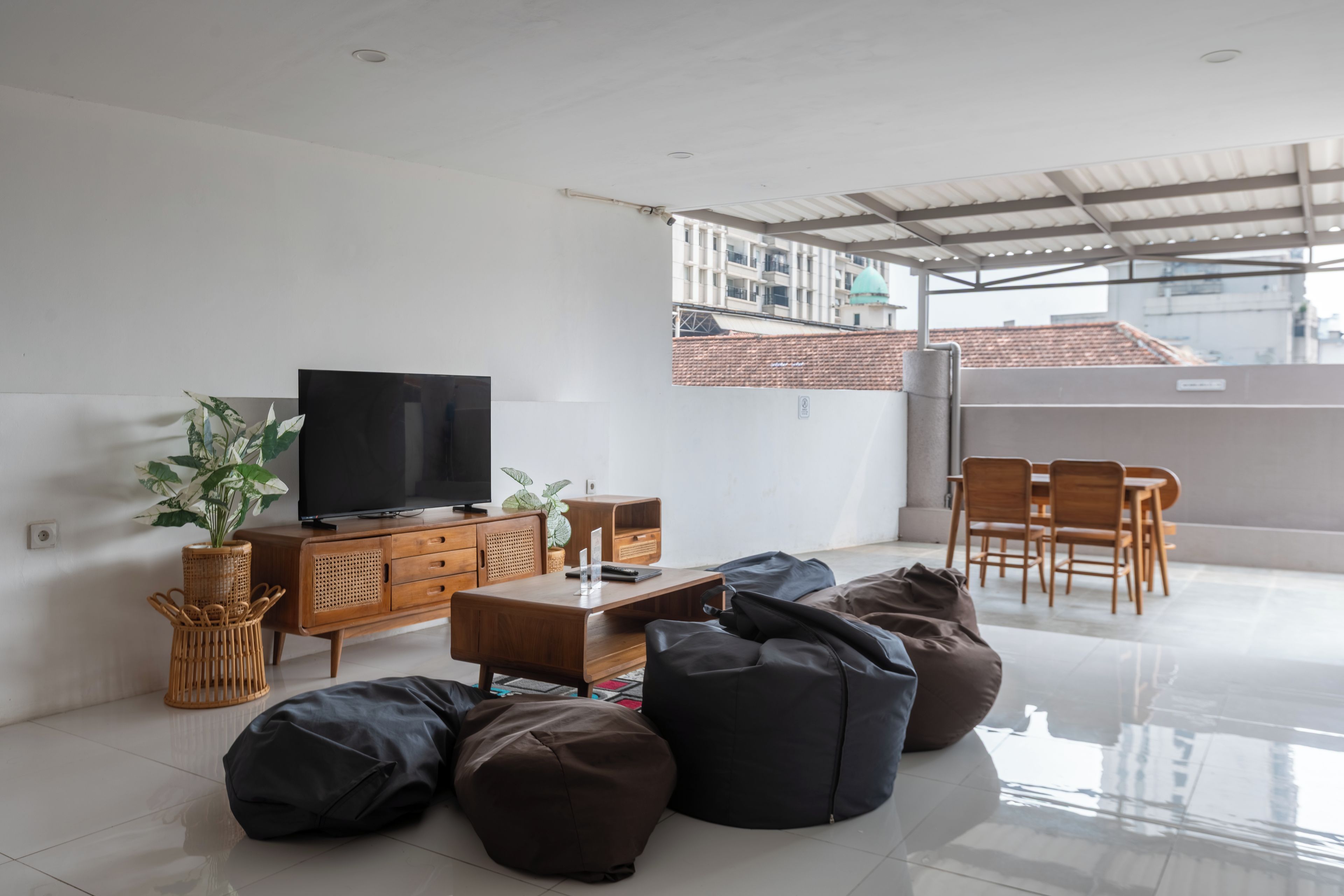 A modern living room with a flat-screen TV, wooden furniture, and a balcony with a view of buildings.