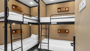 A bunk bed room with wooden headboards and a white wall sign indicating room numbers. - New Hostel Braga (Bandung)