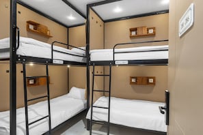 A bunk bed room with wooden headboards and a white wall sign indicating room numbers.