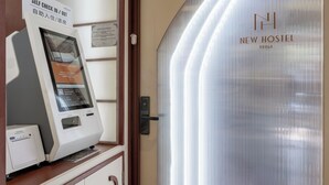 A self-check-in kiosk and a door to the New Hostel in Braga. - New Hostel Braga (Bandung)