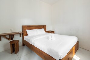 A single bed with a wooden frame and white bedding, flanked by wooden nightstands and a small wooden table. - New Hostel Braga (Bandung)