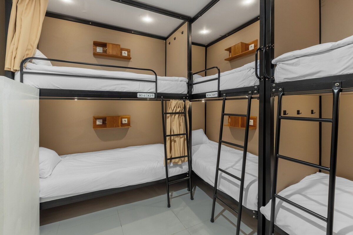 A bunk bed room with a wooden shelf and a curtain.