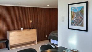 A modern room with a wooden panel wall, a black dining table, a small cabinet, and a framed picture on the wall. - Contempory Hillside studio in Cashmere (Christchurch)