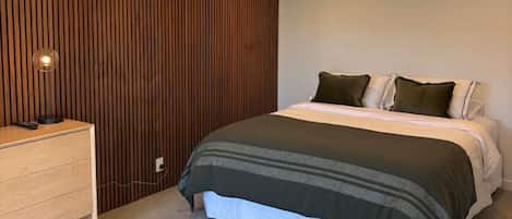 Un dormitorio con cama, mesita de noche y un calentador de pared.