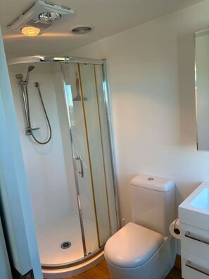 Ein modernes Badezimmer mit einer gläsernen Duschkabine, einer weißen Toilette und einem Waschbecken.
