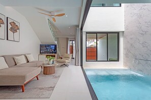 Un salon moderne avec une piscine, un canapé, une table basse et un téléviseur.