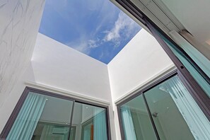 A modern interior with a skylight, large glass doors, and a view of the sky. - Modern Pool Villa Near Bangtoa Beach 5 Mins (Choeng Thale)