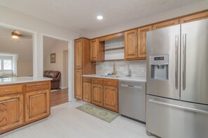 A modern kitchen with wooden cabinets, stainless steel appliances, and a built-in dishwasher. - Plaza on Peacock Ave (Columbus)