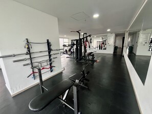 Ein Fitnessstudio mit verschiedenen Trainingsgeräten, darunter Bänke und Gewichtheberstationen.