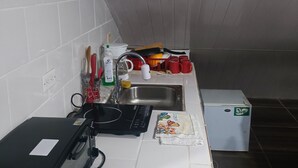 A kitchen with a microwave, sink, and a small refrigerator.