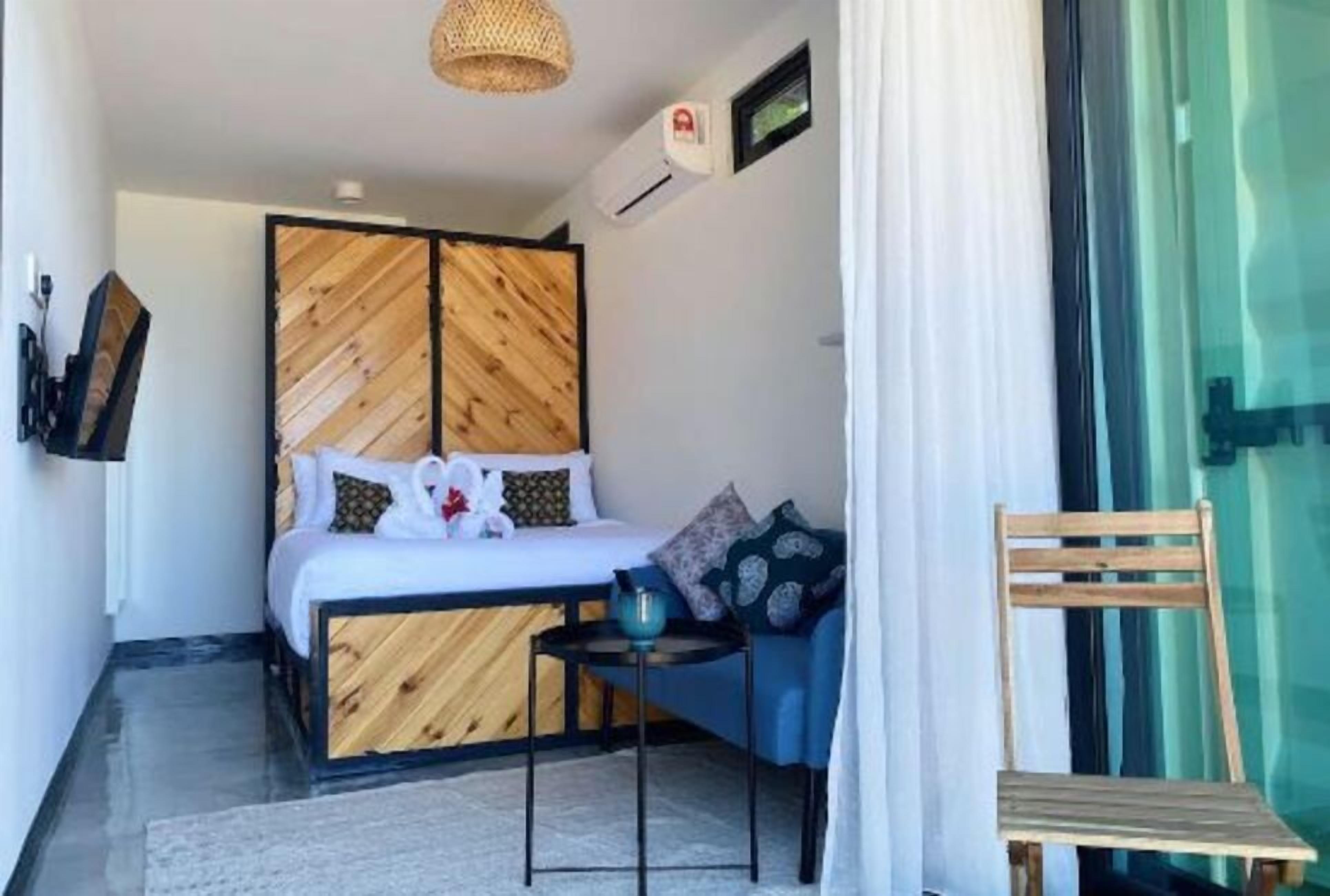 Un dormitorio con una cama, una mesita, una silla y una ventana.