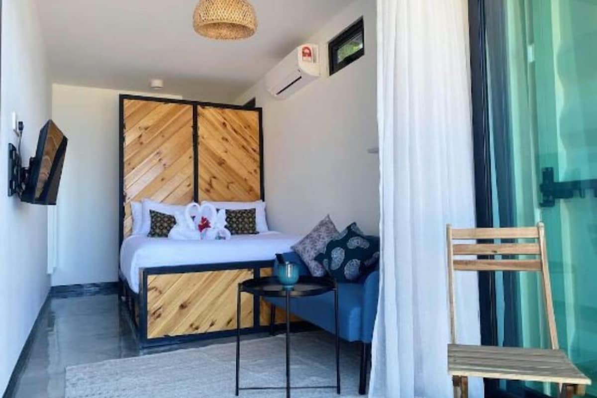 Un dormitorio con una cama, una mesita, una silla y una ventana.