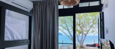 Una habitación con cama, ventana y vista al mar, además de aire acondicionado.