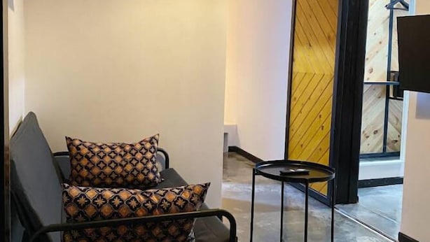 A modern interior with a sofa and a small table, a hanging light fixture, and a wooden partition.