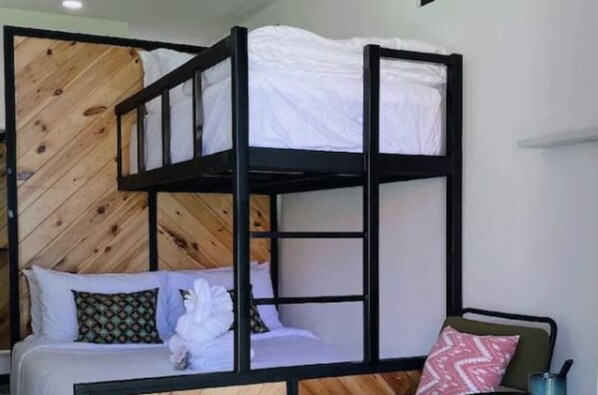 Una cama litera con cabecera de madera, ropa de cama blanca y almohadas estampadas.