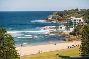A coastal hotel with a beach view, a pool, and a rocky cliff backdrop. - Bondi Penthouse with Panoramic Views (Bondi)