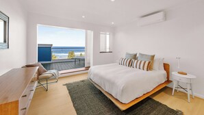 A bedroom with a bed, a desk, a chair, a bedside table, and a view of the ocean. - Bondi Penthouse with Panoramic Views (Bondi)