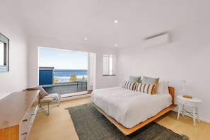 Ein Schlafzimmer mit Bett, Schreibtisch, Stuhl, Nachttisch und Meerblick.