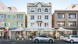 A row of buildings with a central white building featuring arched windows and a balcony. - Bondi Penthouse with Panoramic Views (Bondi)