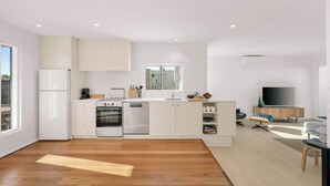 A modern kitchen with built-in appliances, a dining area with a TV, and a large window. - Bondi Penthouse with Panoramic Views (Bondi)