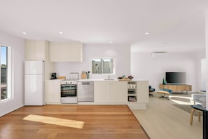 Eine moderne Küche mit Einbaugeräten, ein Essbereich mit Fernseher und ein großes Fenster.